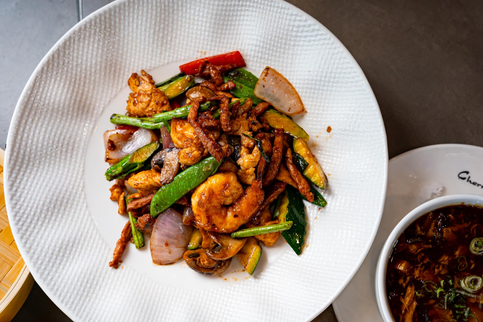 Wok-sauteed shrimp with vegetables on a white plate