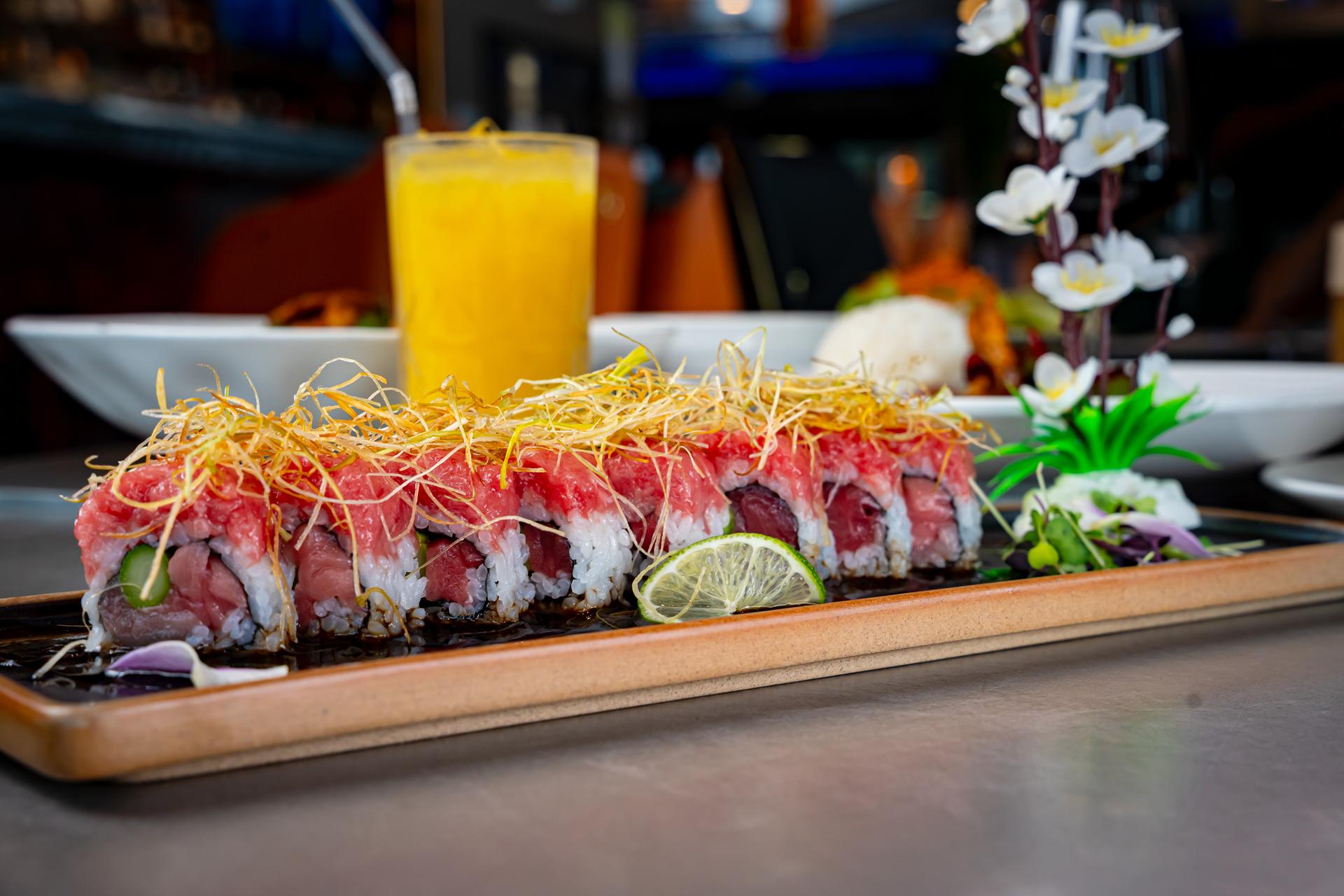 Signature sushi roll with crispy topping on a wooden board at Cherry Amber