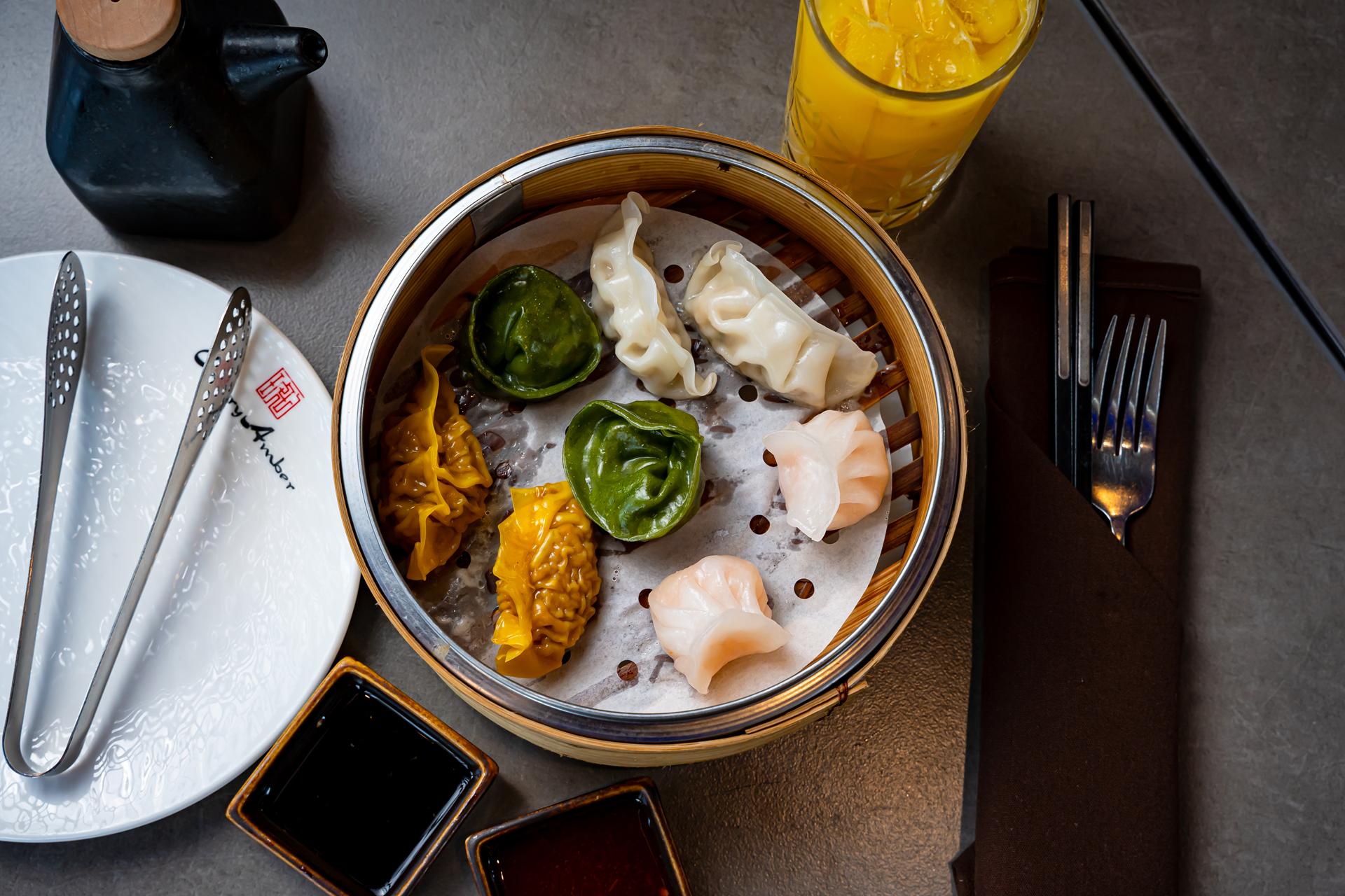 Steamed dim sum dumplings in a bamboo steamer with dipping sauces